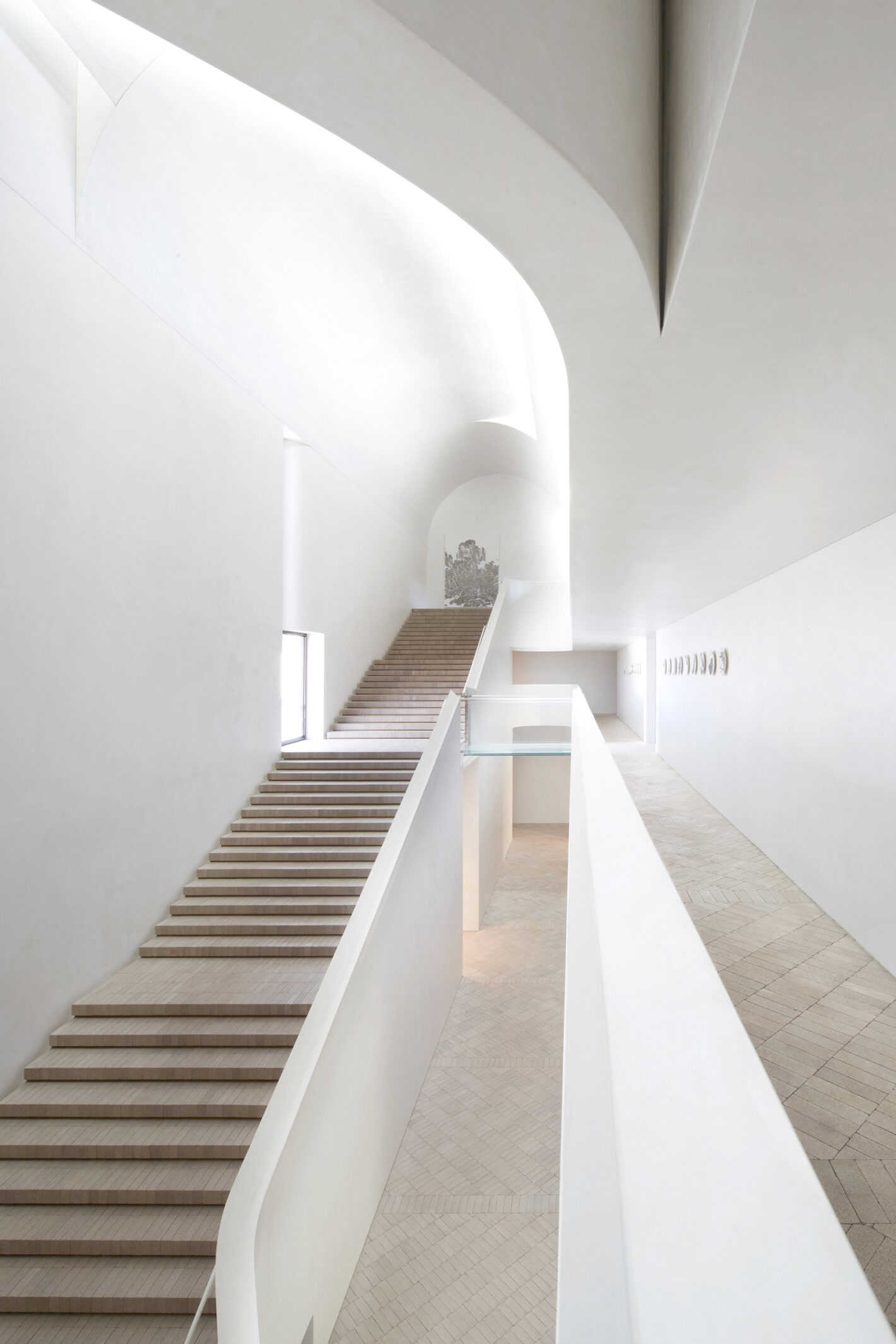 Cavernous stair hall of Indigo Slam, illuminated by concealed roof lights, featuring minimalist design elements and expansive space.