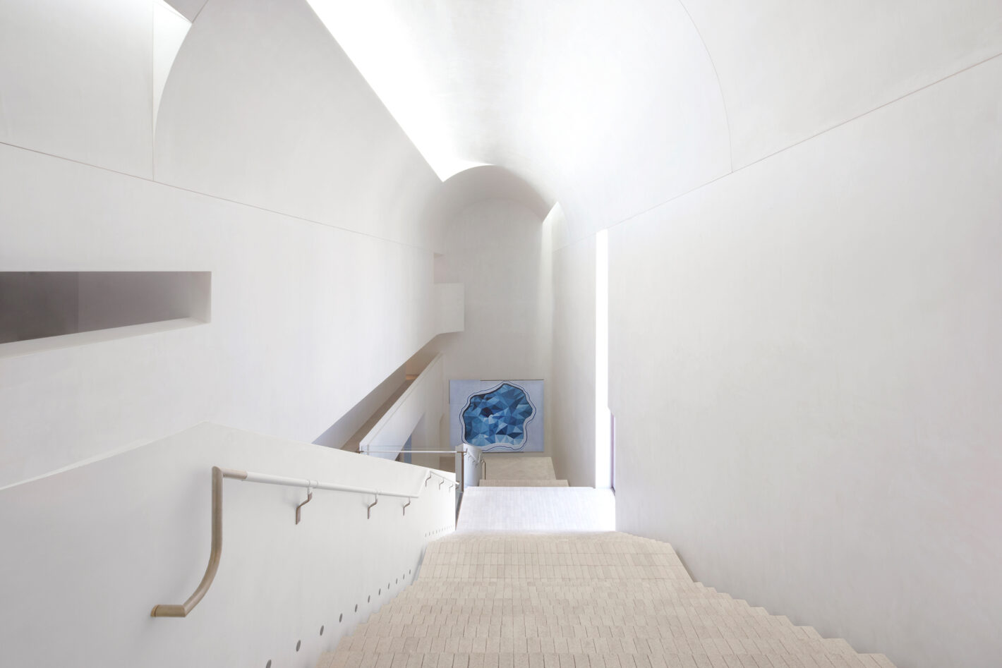Cavernous stair hall of Indigo Slam, illuminated by concealed roof lights, featuring minimalist design elements and expansive space.